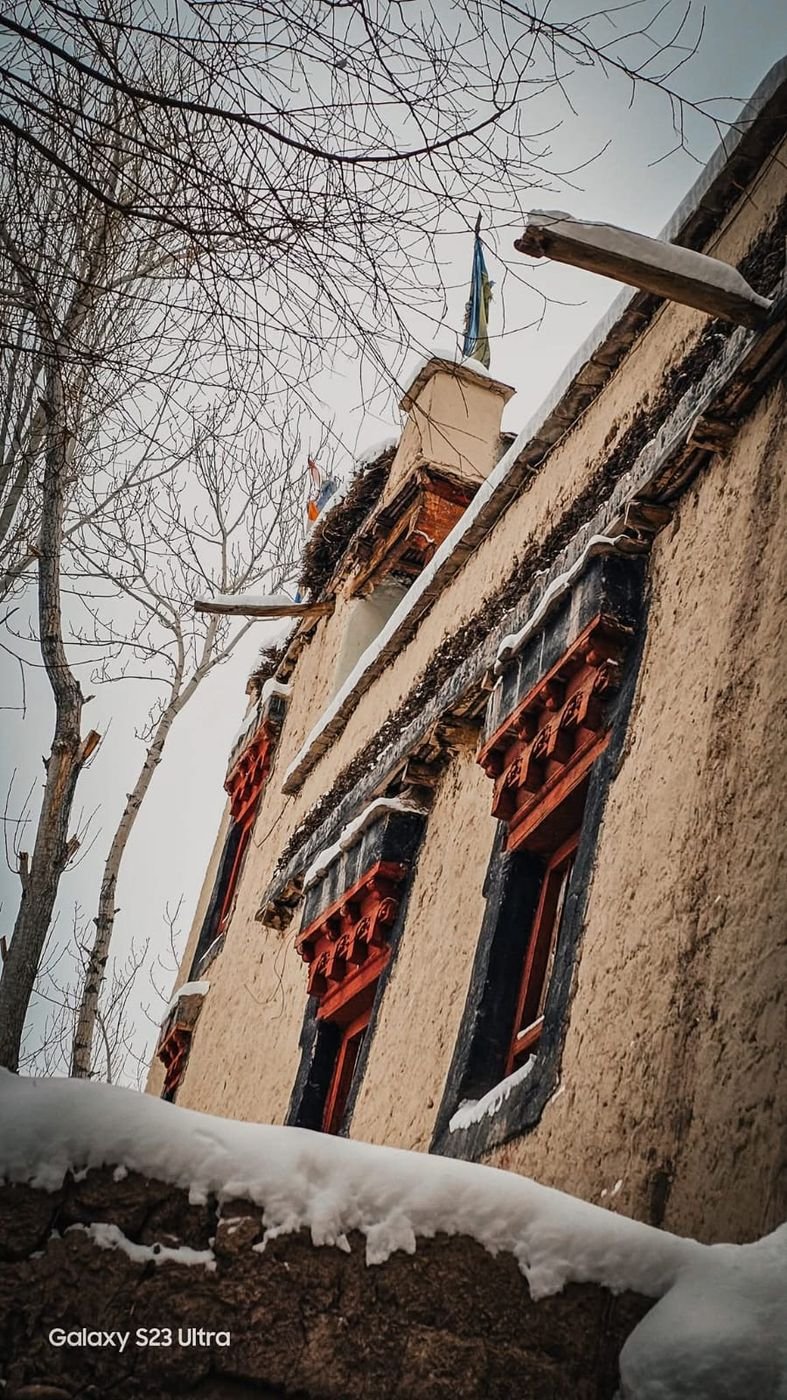 Mud walls and red-framed windows in the snow