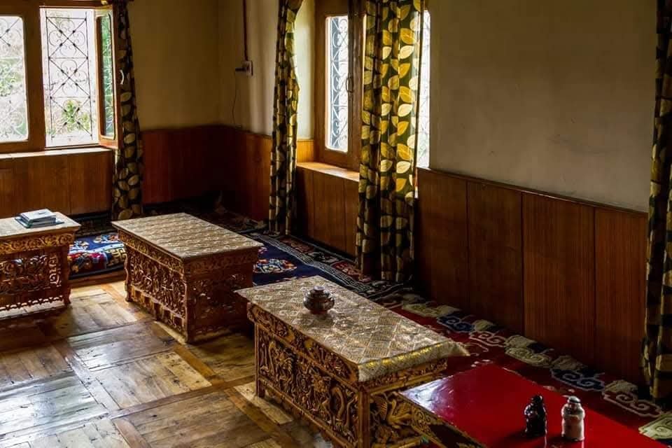 Traditional Ladakhi sitting room with carved low tables and wooden floors